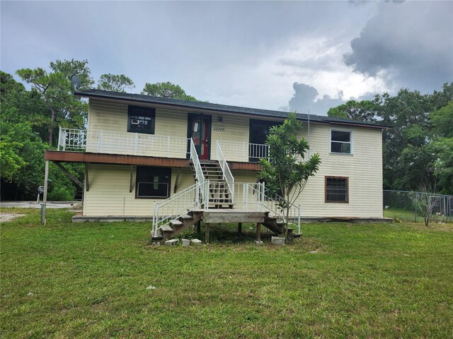 view of front of property with stairs, a front lawn, and fence