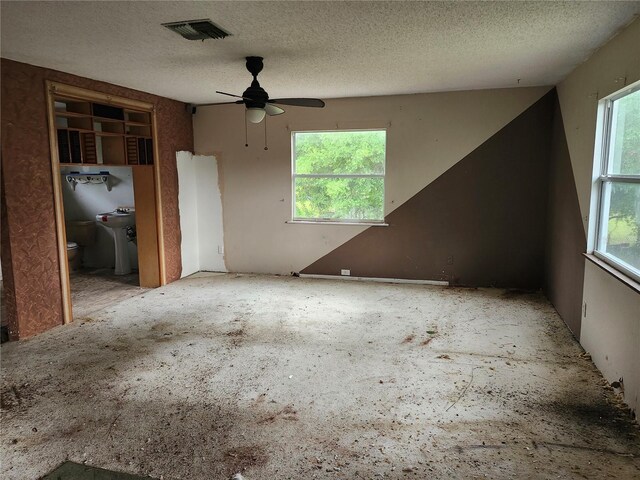 unfurnished bedroom with connected bathroom, visible vents, ceiling fan, and a textured ceiling