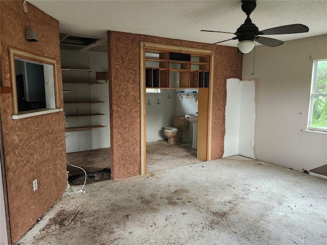 unfurnished bedroom featuring a ceiling fan, connected bathroom, and a textured ceiling