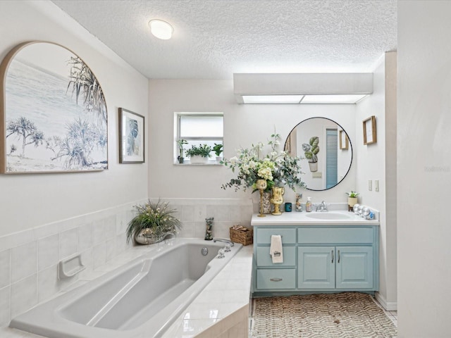 bathroom featuring vanity, tile patterned floors, tiled bath, and a textured ceiling