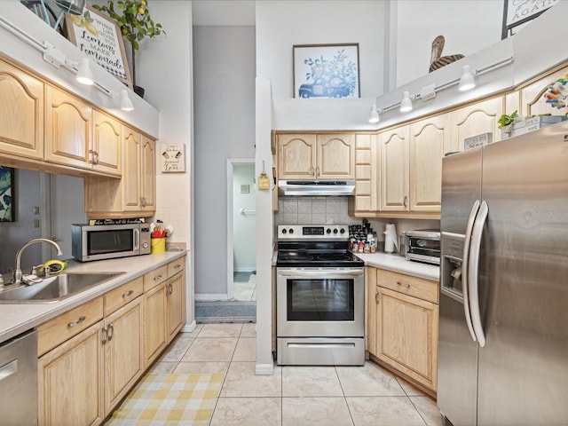 kitchen featuring light brown cabinetry, sink, tasteful backsplash, appliances with stainless steel finishes, and a towering ceiling