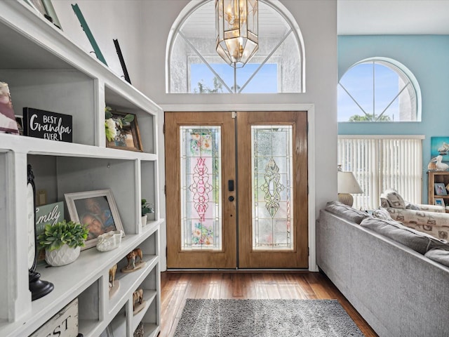 entrance foyer featuring hardwood / wood-style flooring, a high ceiling, an inviting chandelier, and french doors