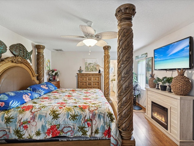 bedroom featuring ceiling fan, hardwood / wood-style floors, and a textured ceiling