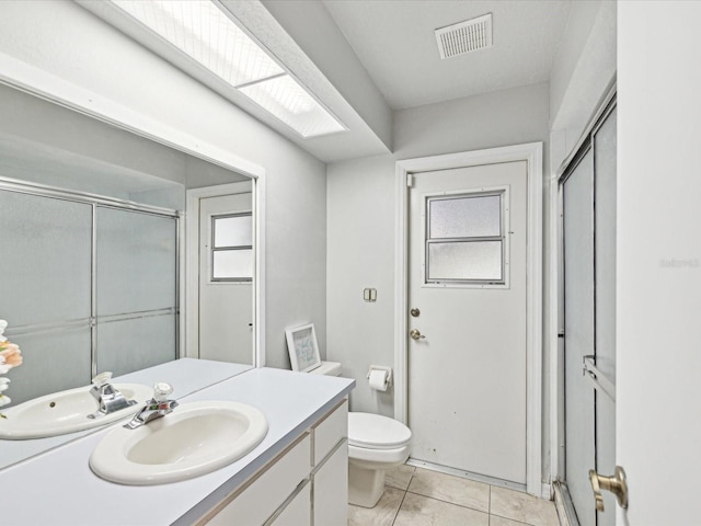 bathroom featuring an enclosed shower, vanity, tile patterned floors, and toilet