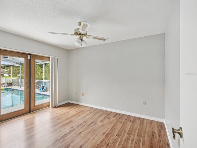 empty room with ceiling fan, light hardwood / wood-style floors, french doors, and a textured ceiling