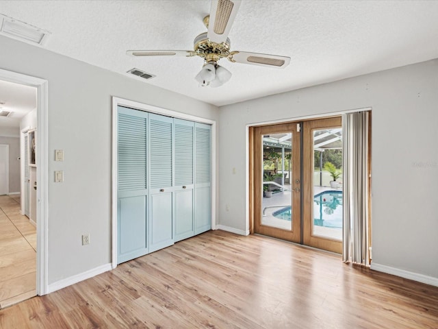 unfurnished bedroom featuring light wood-type flooring, access to exterior, ceiling fan, a textured ceiling, and a closet