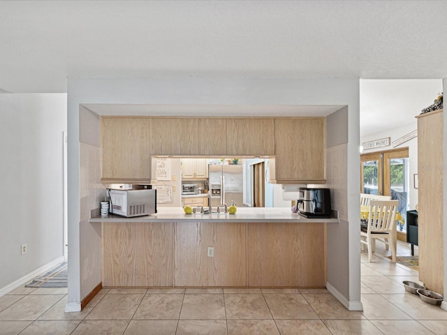 kitchen featuring stainless steel refrigerator with ice dispenser, light tile patterned floors, light brown cabinetry, and kitchen peninsula