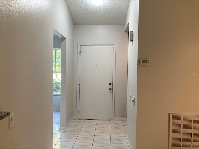 doorway to outside featuring a textured ceiling and light tile patterned floors