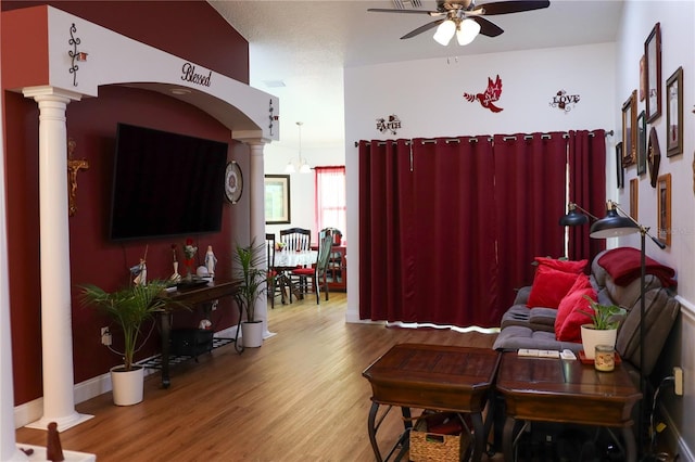 living room featuring wood-type flooring, ceiling fan, and ornate columns