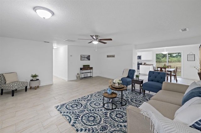 living room with ceiling fan and a textured ceiling