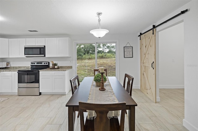 dining room with a barn door and a textured ceiling