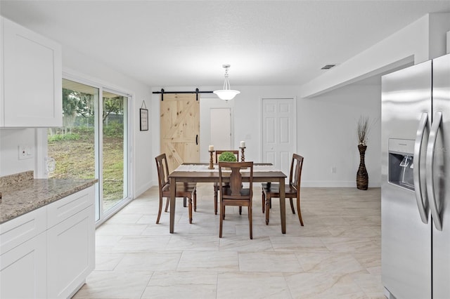 dining area with a barn door and a textured ceiling