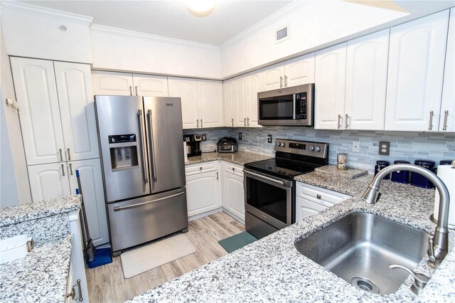 kitchen featuring stainless steel appliances, light stone countertops, sink, and white cabinets