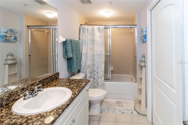 full bathroom with vanity, a textured ceiling, tile patterned floors, toilet, and tiled shower / bath