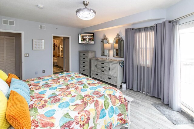 bedroom featuring ensuite bath and light wood-type flooring