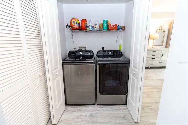 laundry area with washer and dryer and light wood-type flooring