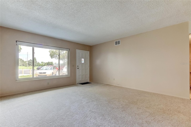 empty room featuring light colored carpet and a textured ceiling