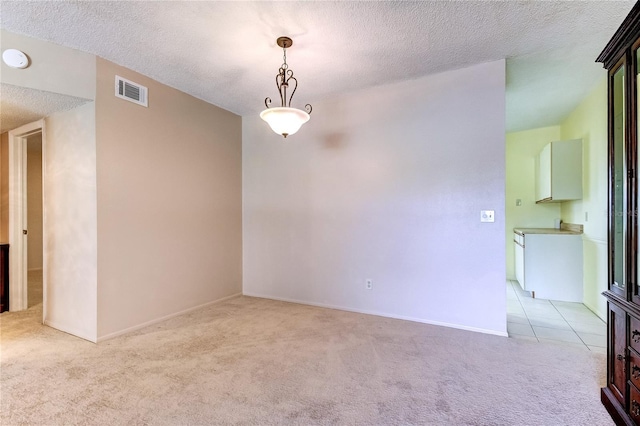 empty room with light carpet and a textured ceiling