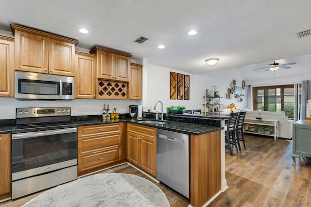 kitchen featuring hardwood / wood-style floors, sink, kitchen peninsula, and stainless steel appliances