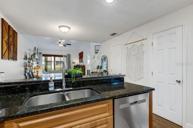 kitchen featuring a textured ceiling, dark hardwood / wood-style floors, stainless steel dishwasher, and sink