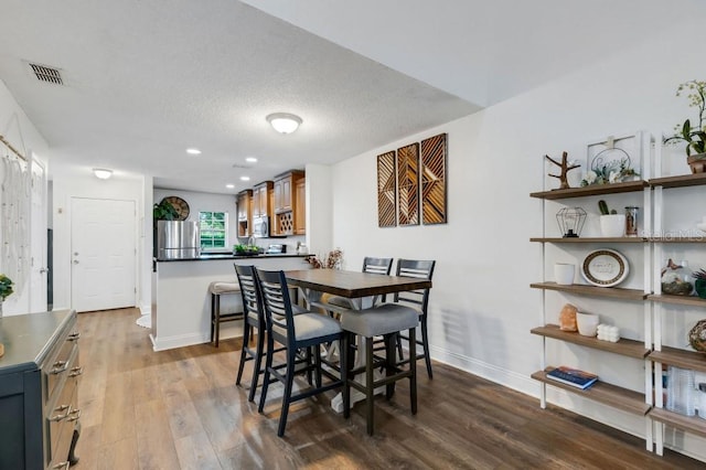 dining area with light hardwood / wood-style flooring and a textured ceiling