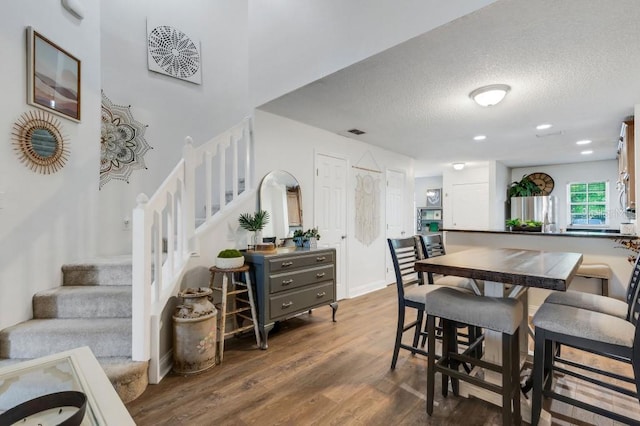 dining space with hardwood / wood-style flooring and a textured ceiling