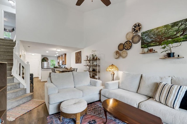 living room featuring a wealth of natural light, ceiling fan, wood-type flooring, and a high ceiling