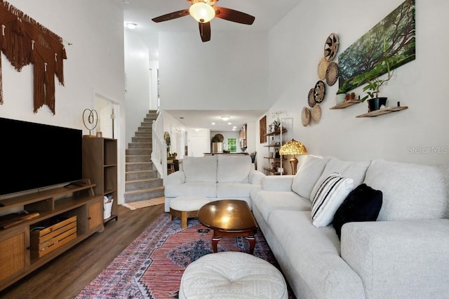 living room with a high ceiling, dark hardwood / wood-style flooring, and ceiling fan