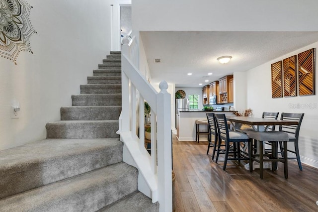 stairway with hardwood / wood-style flooring and a textured ceiling