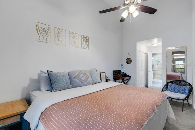 carpeted bedroom with connected bathroom, ceiling fan, and a high ceiling