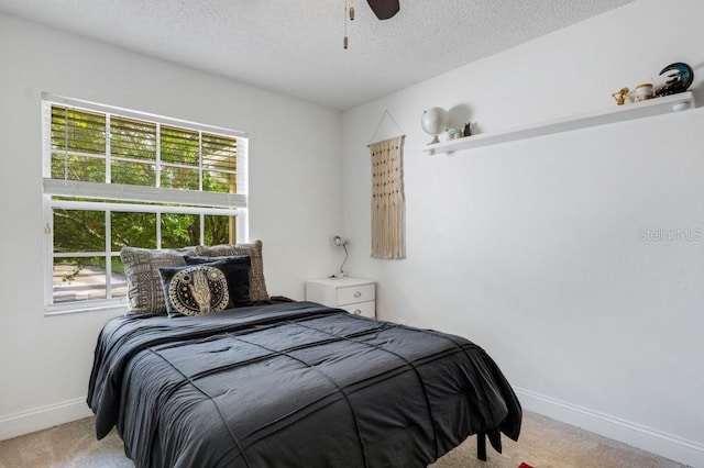 bedroom featuring ceiling fan, light colored carpet, and a textured ceiling