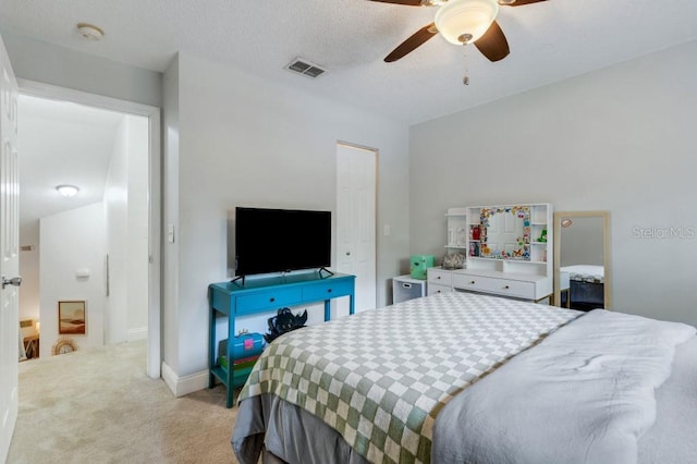 carpeted bedroom featuring ceiling fan and a textured ceiling