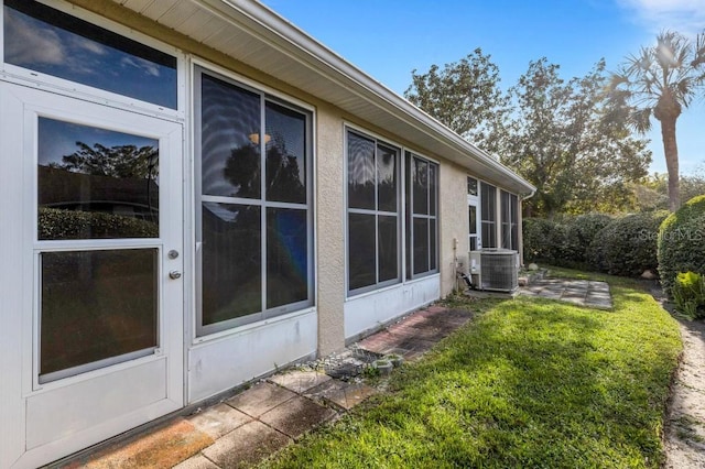 view of side of property with a lawn and central AC