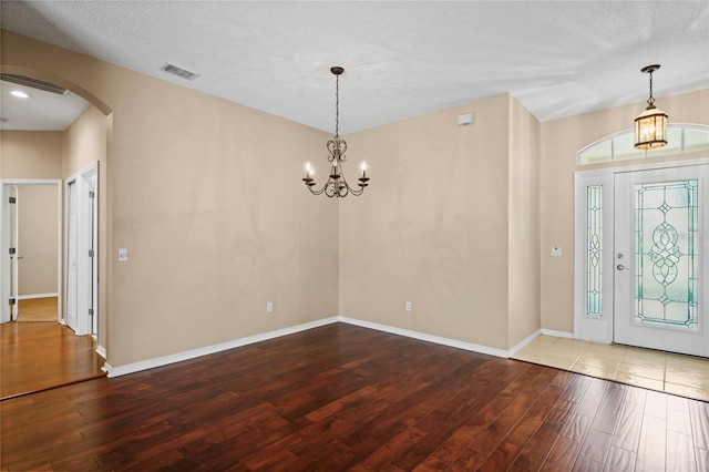 foyer with hardwood / wood-style floors, a textured ceiling, and a notable chandelier