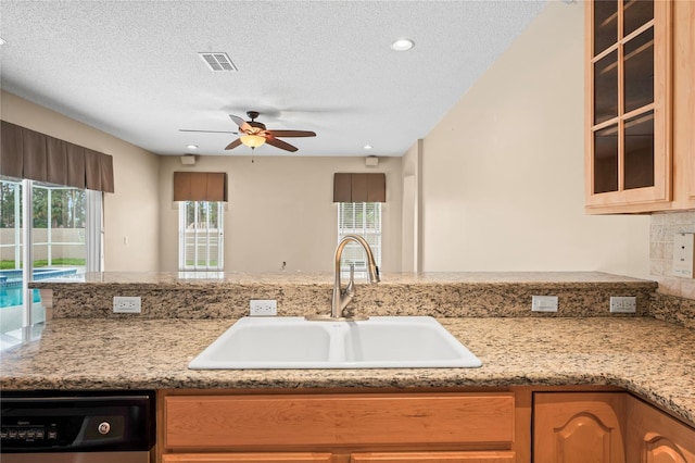 kitchen with sink, a textured ceiling, dishwashing machine, and a wealth of natural light