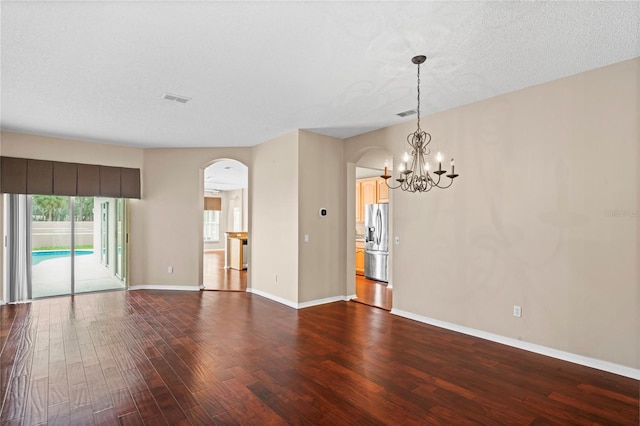 unfurnished room with hardwood / wood-style floors, a textured ceiling, and a notable chandelier