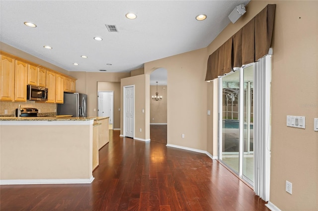 kitchen featuring light stone counters, decorative backsplash, stainless steel appliances, and a healthy amount of sunlight