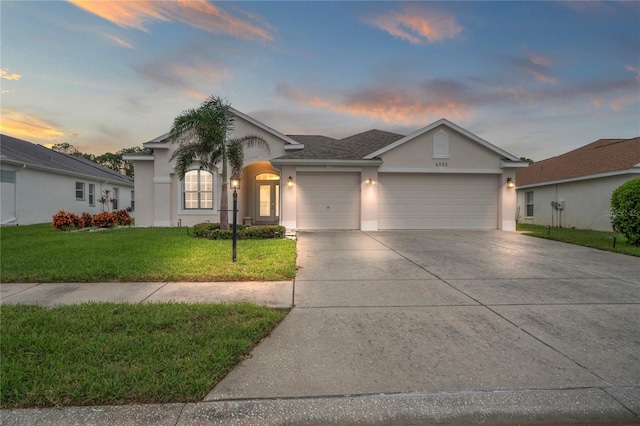 ranch-style home featuring a lawn and a garage