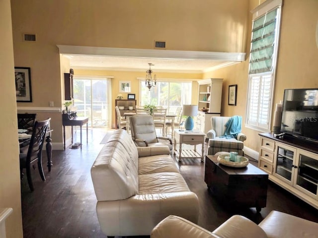 living room with dark hardwood / wood-style flooring, ornamental molding, a wealth of natural light, and an inviting chandelier