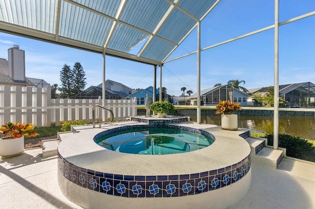 view of swimming pool with an in ground hot tub, a water view, a patio area, and glass enclosure