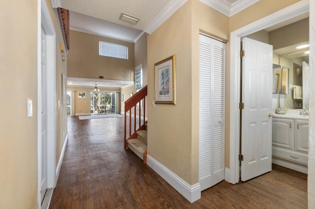 corridor with crown molding, dark wood-type flooring, and a textured ceiling