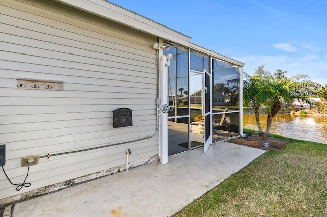 view of exterior entry featuring a patio, a water view, and a yard