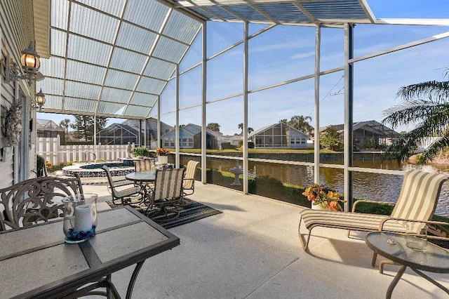 view of patio featuring an in ground hot tub, glass enclosure, and a water view