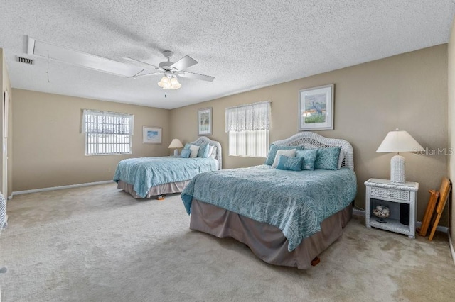 carpeted bedroom featuring ceiling fan and a textured ceiling