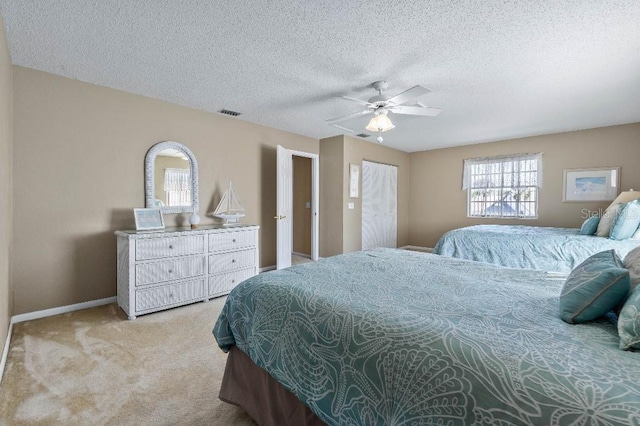 bedroom with ceiling fan, light carpet, and a textured ceiling