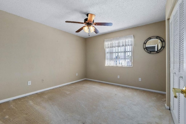 carpeted empty room with ceiling fan and a textured ceiling