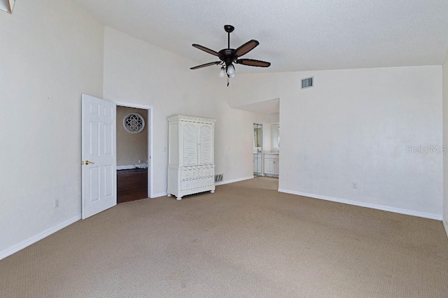 unfurnished bedroom with ceiling fan, high vaulted ceiling, ensuite bathroom, and carpet floors