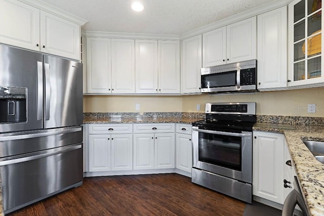 kitchen featuring stainless steel appliances, dark hardwood / wood-style floors, light stone countertops, and white cabinets