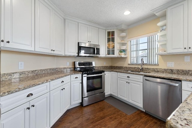 kitchen featuring appliances with stainless steel finishes, sink, white cabinets, light stone countertops, and dark wood-type flooring