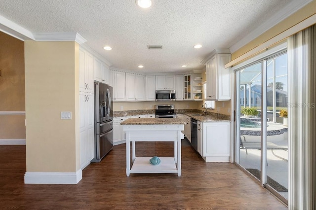 kitchen featuring appliances with stainless steel finishes, light stone countertops, a kitchen island, and white cabinets